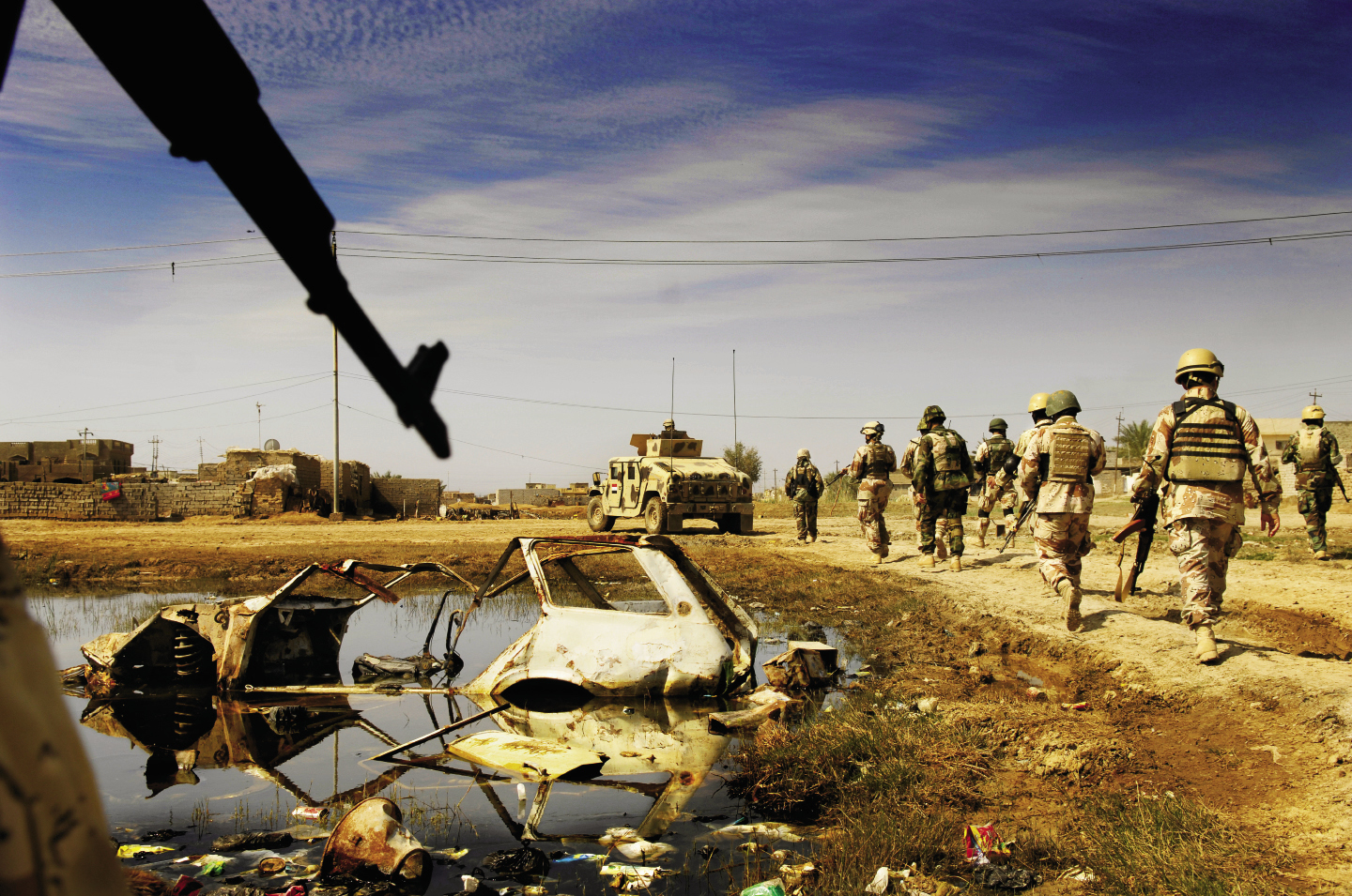 March 4, 2007: Iraqi Army soldiers march past a car destroyed during a prior operation in New Baqubah, Iraq. The operation aimed to eliminate the area as a base for anti-Iraqi forces building I.E.D.s (improvised explosive devices).
