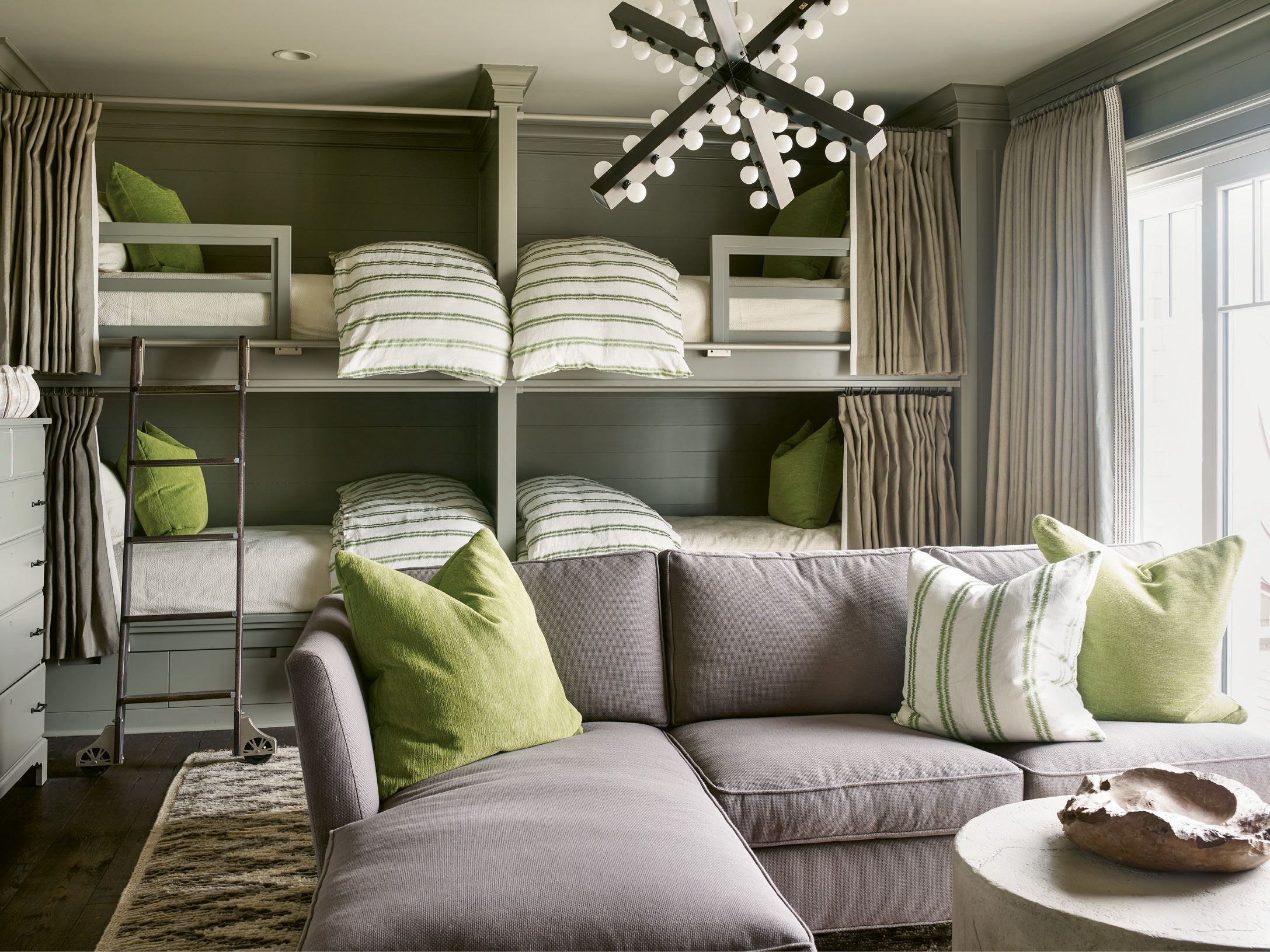 The bunk room’s cool comforts include the slate grey walls, shag Moroccan carpet, and pops of lime green.