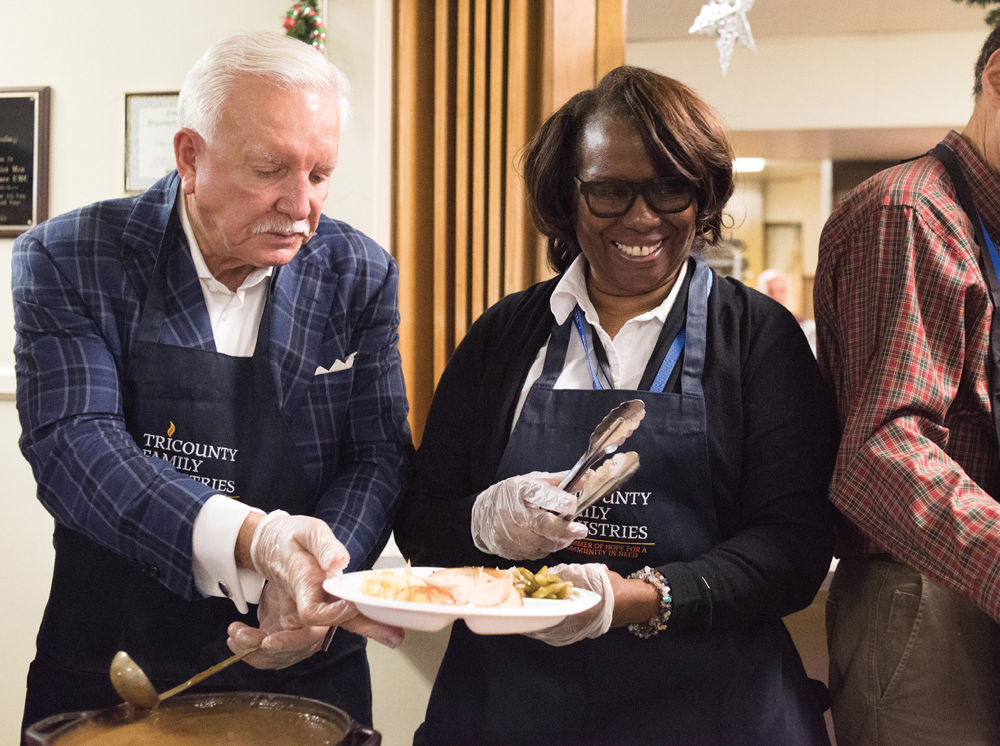 Volunteers Tommy Baker and Felicia Sanders help dish up hot fare for shelter clients.