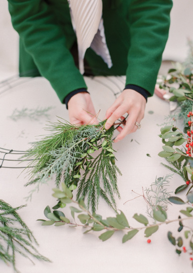 A workshop-goer puts together a spray of evergreen sprigs, including pine, sapphire cedar, and boxwood.
