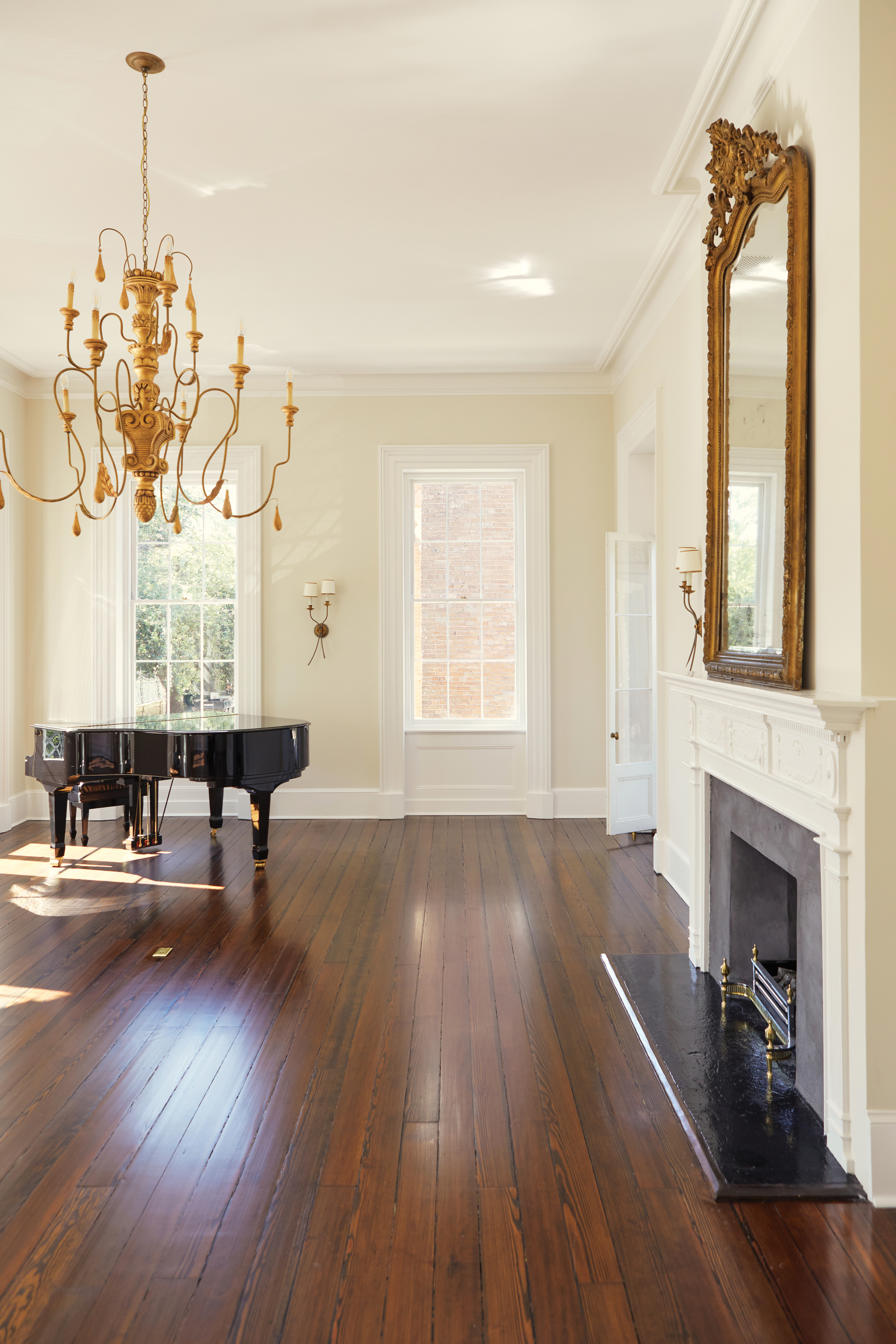 At the front of the house, this stately, second-floor room has been restored to its original purpose: a spacious ballroom for entertaining and dancing. The grand piano, gold-leaf chandelier and mirror, and antique wicker chaise lounge evoke thoughts of 19th-century soirees within the pale plaster walls.