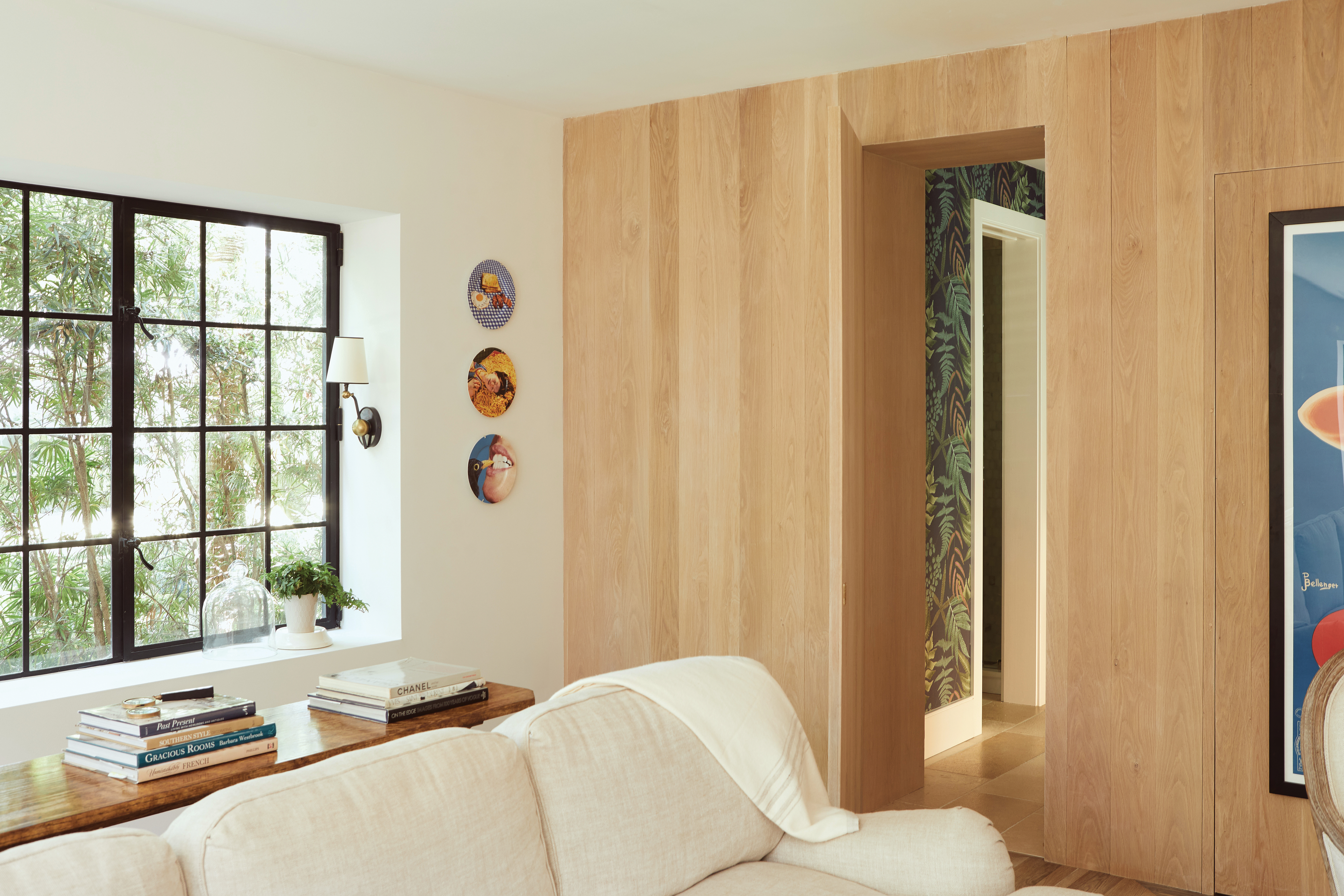 The comfortable den, just beyond the boldly patterned laundry room is where Anne and Jon spend most of their time. Once a garage, the space converts into a self-contained guest suite, its white oak walls hiding a Murphy bed.