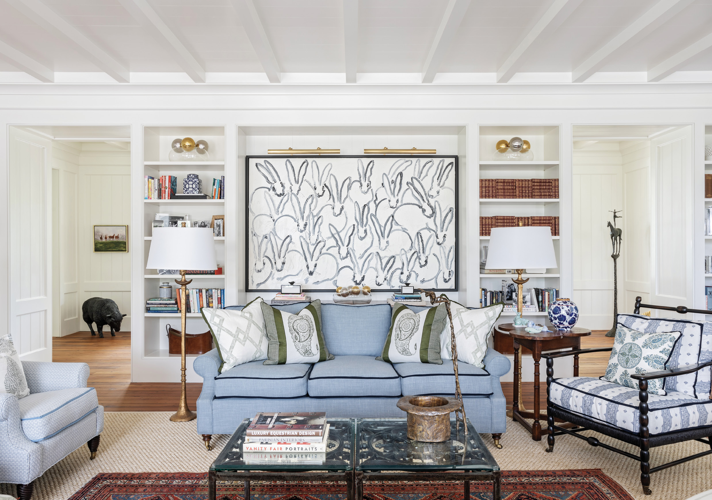 The architects designed spaces for the client’s artwork, such as this built-in made for Hunt Slonem’s Bunnies. Interior designer Melissa Ervin designed the living room to be comfortable and livable with a green and blue color palette playing on the natural scene beyond its large windows. The Edward Ferrell sofa is covered in CalvinFabric’s “Camino-Lake,” tipped with grosgrain ribbon, a small detail with a large impact.