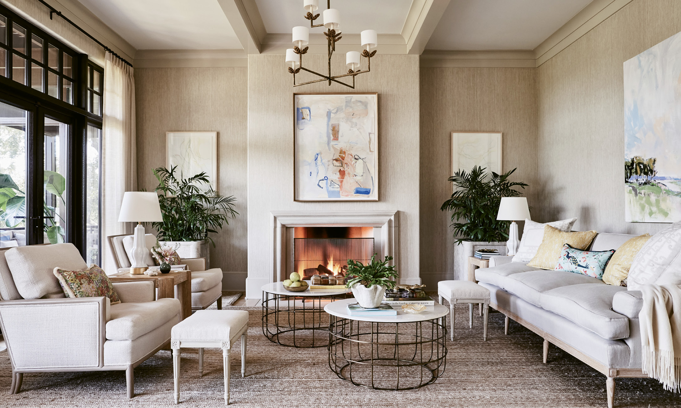Neutral Territory: In the living room, a neutral yet textured sandy palette, including grasscloth-covered walls and upholstered linen sofa and chairs, allows the expansive marsh view to take center stage. The Frank Phillips painting over the mantel, found at George Gallery, as well as some commissioned works, provide splashes of subtle color. Bamboo and brass accents add dimension.