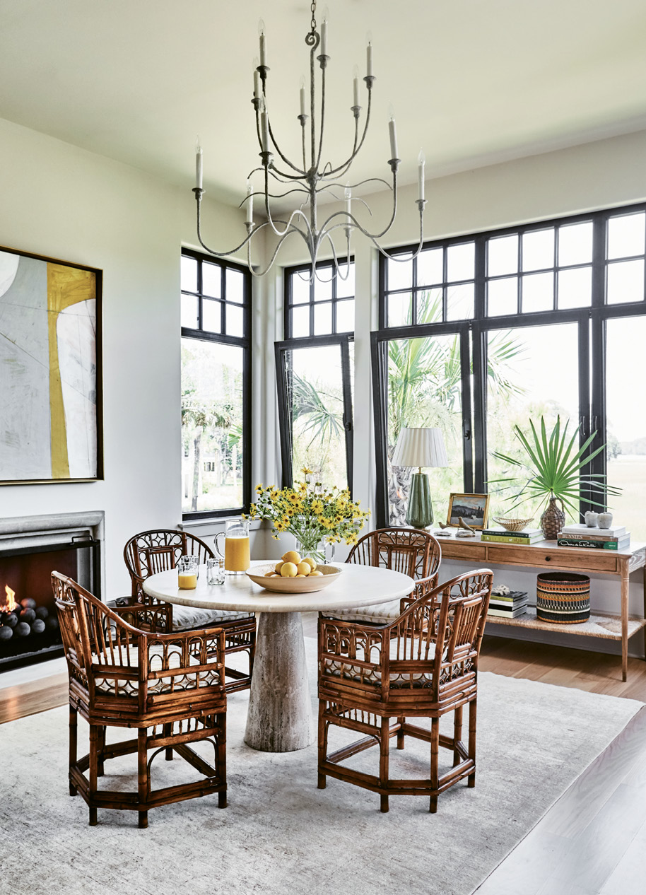 NATURALLY ELEGANT: Henselstone three-tilt transom windows from Germany give definition to the airy breakfast room, which is outfitted with organic furnishings, including a travertine pedestal table from a Palm Beach antiques shop and vintage Brighton rattan armchairs.