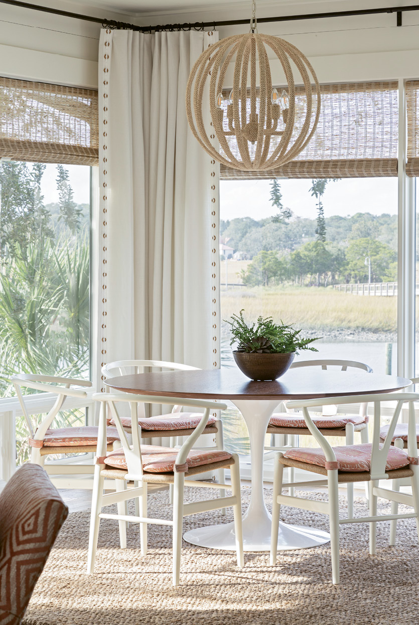A simple walnut, tulip-based breakfast table, watched over by a coco-bead chandelier from Palecek, offers idyllic views of the creek and the Ravenel Bridge.