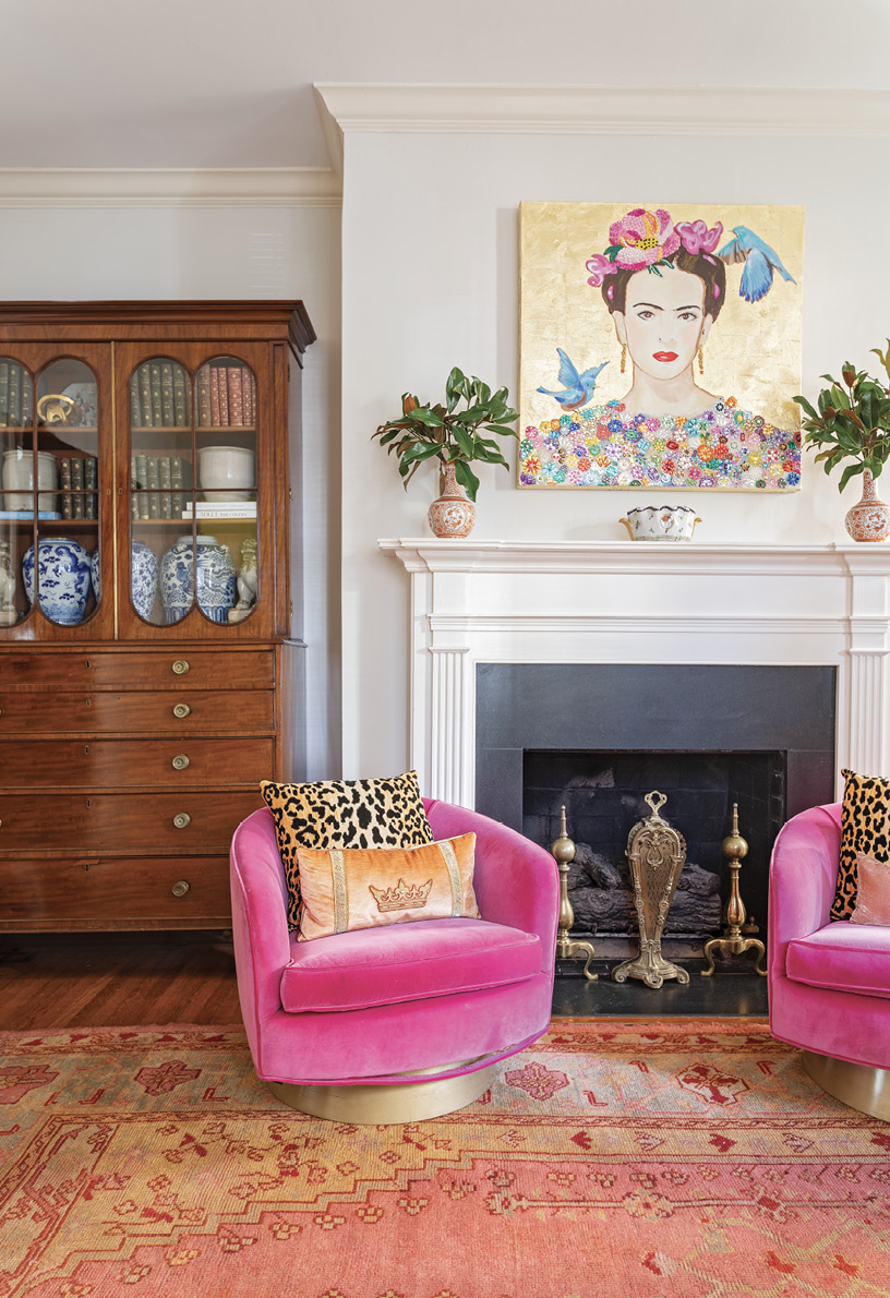 MIXED-CENTURY MOD: Hanging above the room’s original fireplace, a mixed-media portrait of Frida Kahlo by Ashley Longshore watches over the blend of eras in the decor—including two uber-modern club chairs; an antique Turkish rug; and the traditional armoire, a family heirloom—that typifies the grandmillenial style.