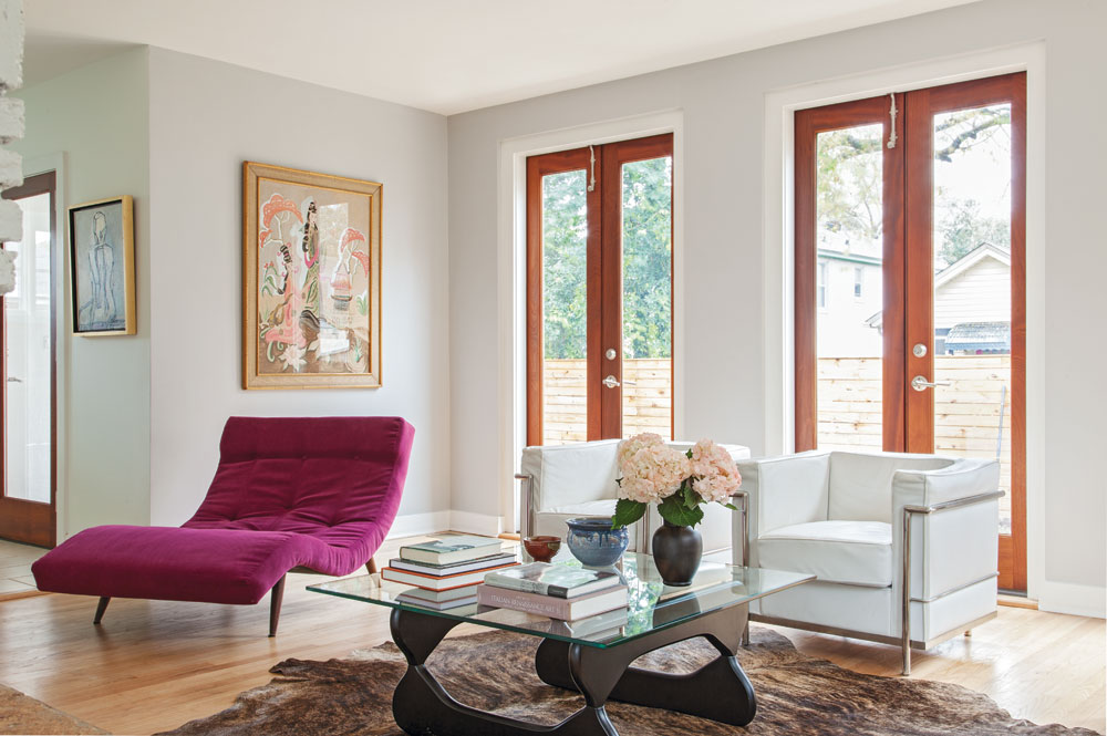 BY DESIGN: In the living room, a few strategic design tweaks made a big impact. A row of windows were swapped out for sapele French doors, strengthening the relationship between the living area and the outdoors. A chaise lounge was recovered in an eye-catching purple hue to suit the home’s new vibe.