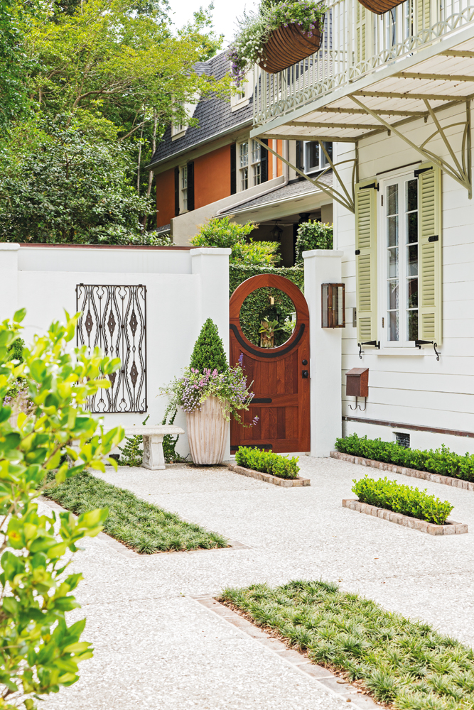 Curb Appeal: Landscape architect Glen R. Gardner defined the front entrance with a mahogany gateway and softened the driveway with boxwoods, mondo grass, and an olive tree.