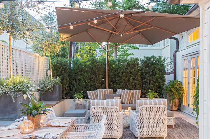 Garden Party: Upholstered furnishings from Barlow Tyrie, lead planters from Restoration Hardware, and custom ipe wood benches set an inviting scene under the shade of a giant Tuuci umbrella.
