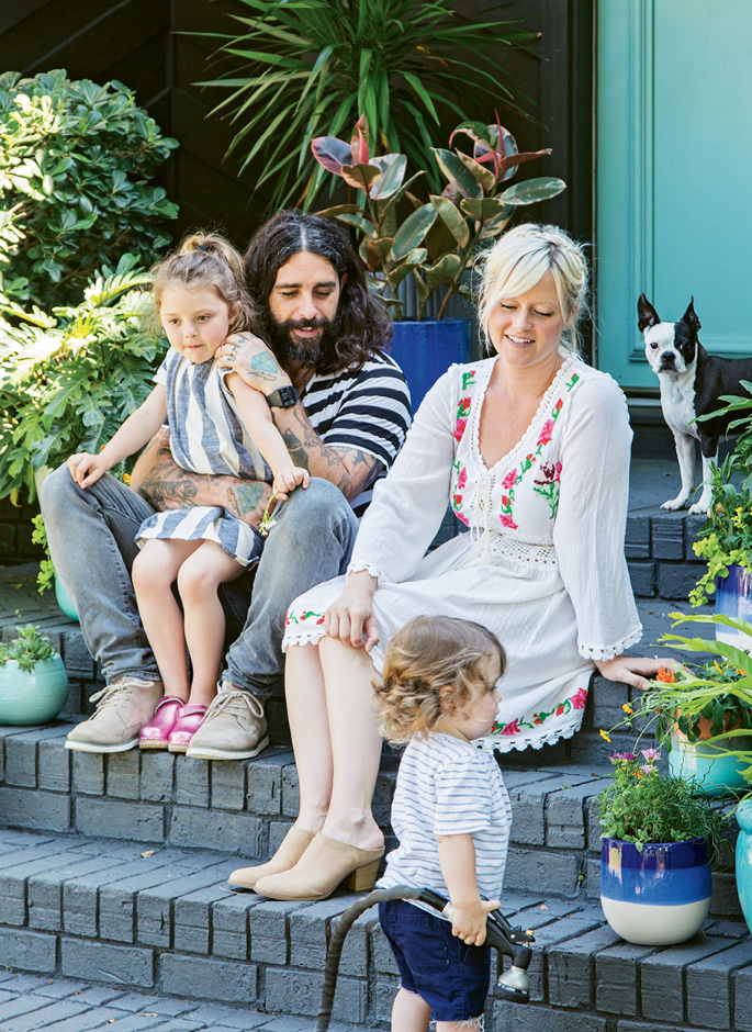 ROCKING THE SUBURBS: Erin and Creighton Barrett kick back on their front steps with Sunny, age five, and Bowie, almost two. To accommodate their growing family, the creative couple—he drums with Band of Horses, she’s a textile artist—traded a cottage in Avondale for this roomier ’70s ranch near Charles Towne Landing.