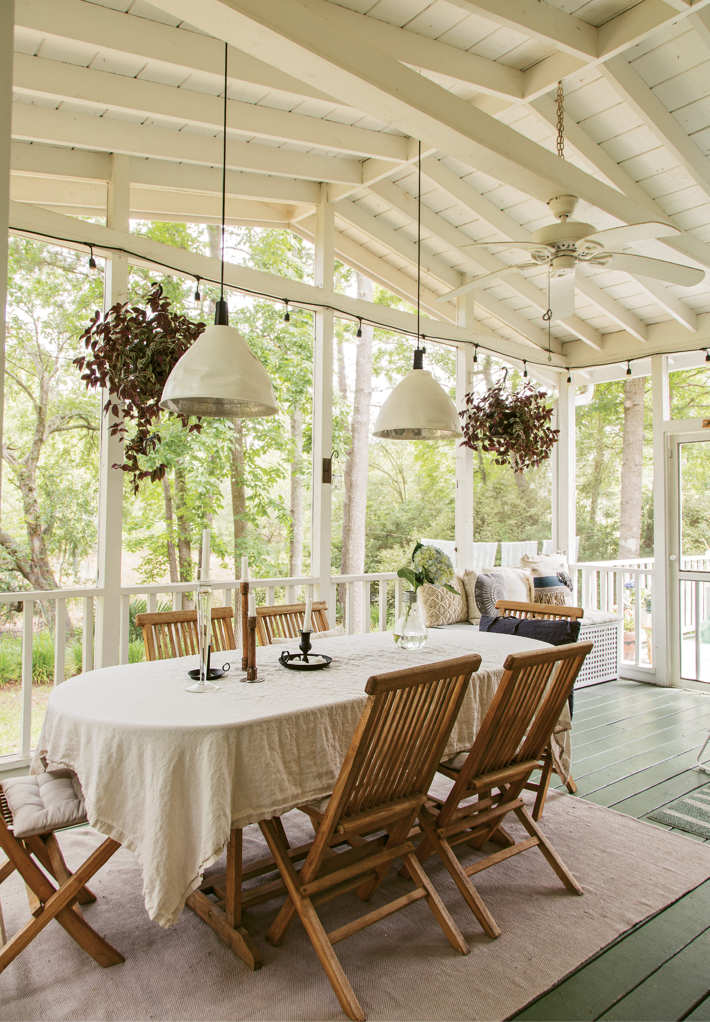 PORCH PARADISE: Winters in Gothenburg are harsh, so Therese and Jacob are loving the Lowcountry’s mild climate. Mature trees and a long creek view make dining alfresco particularly pleasant, as do rustic wooden chairs, simple white linens, and soft light from pendant lamps and candles.