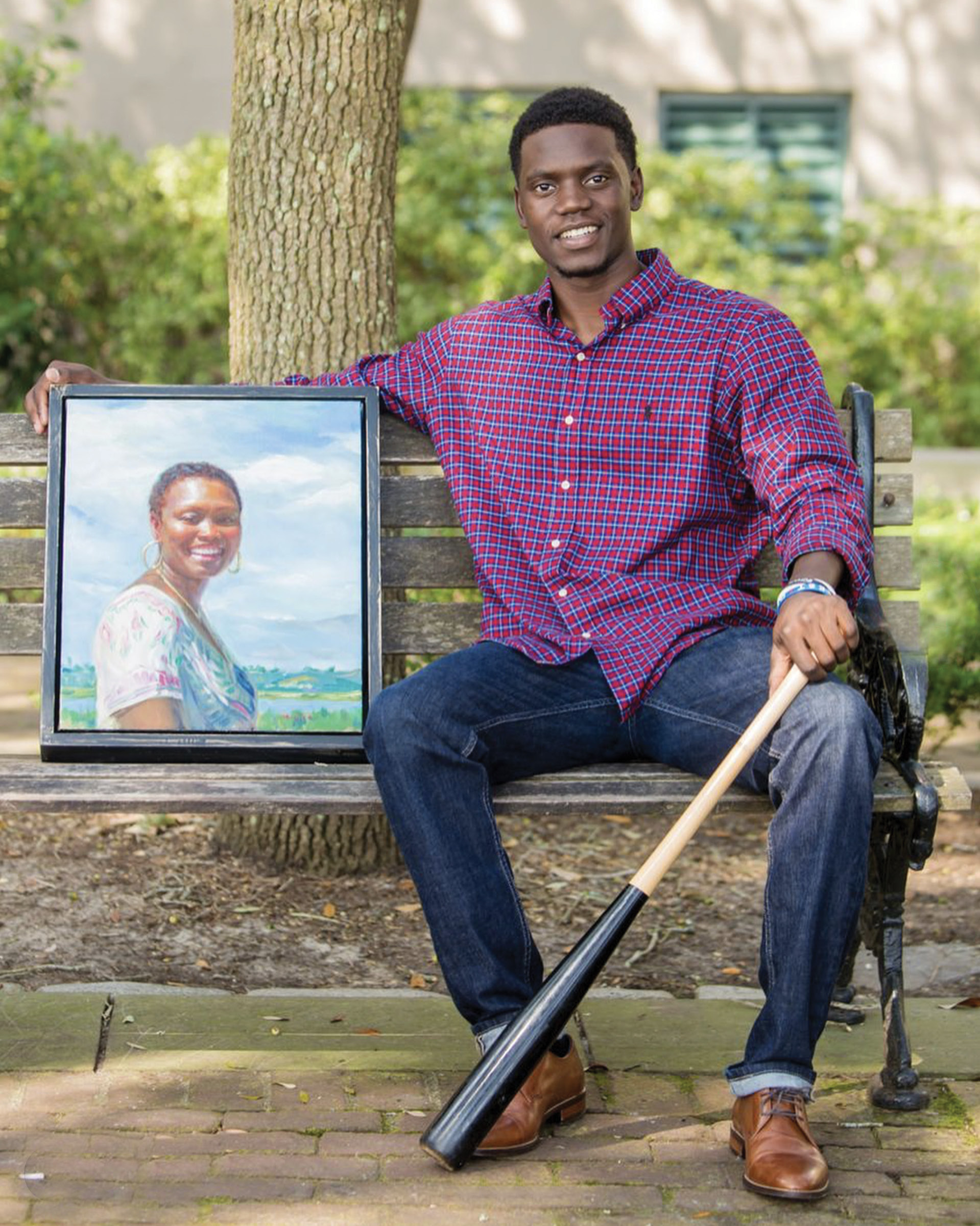 Chris Singleton, a former professional baseball player who is now an inspirational speaker and employee of the RiverDogs, with a portrait of his late mother painted by Ricky Mujica.
