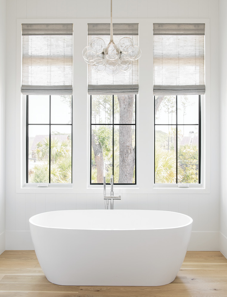 In the adjoining bathroom, a large bubble chandelier from Pelle hangs above a Mirabelle freestanding tub.