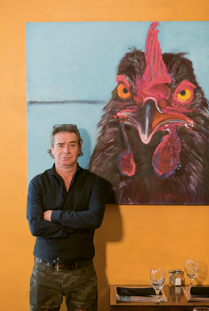 Chick Magnet: Goulette chef-owner Perig Goulet poses with one of the cafe’s cheeky chicken paintings, this one by local artist Sybil Fix.