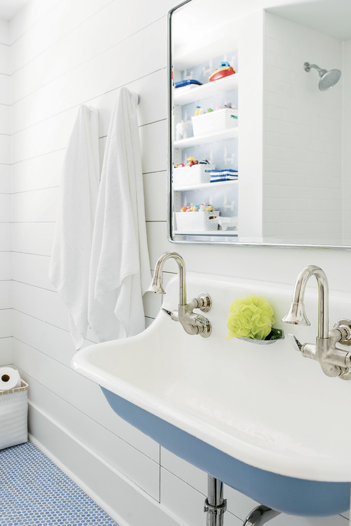 Shiplap walls, penny-tile floors, simple towel hooks, and a trough sink make for a splash-safe (and stylish) backdrop to bath time.