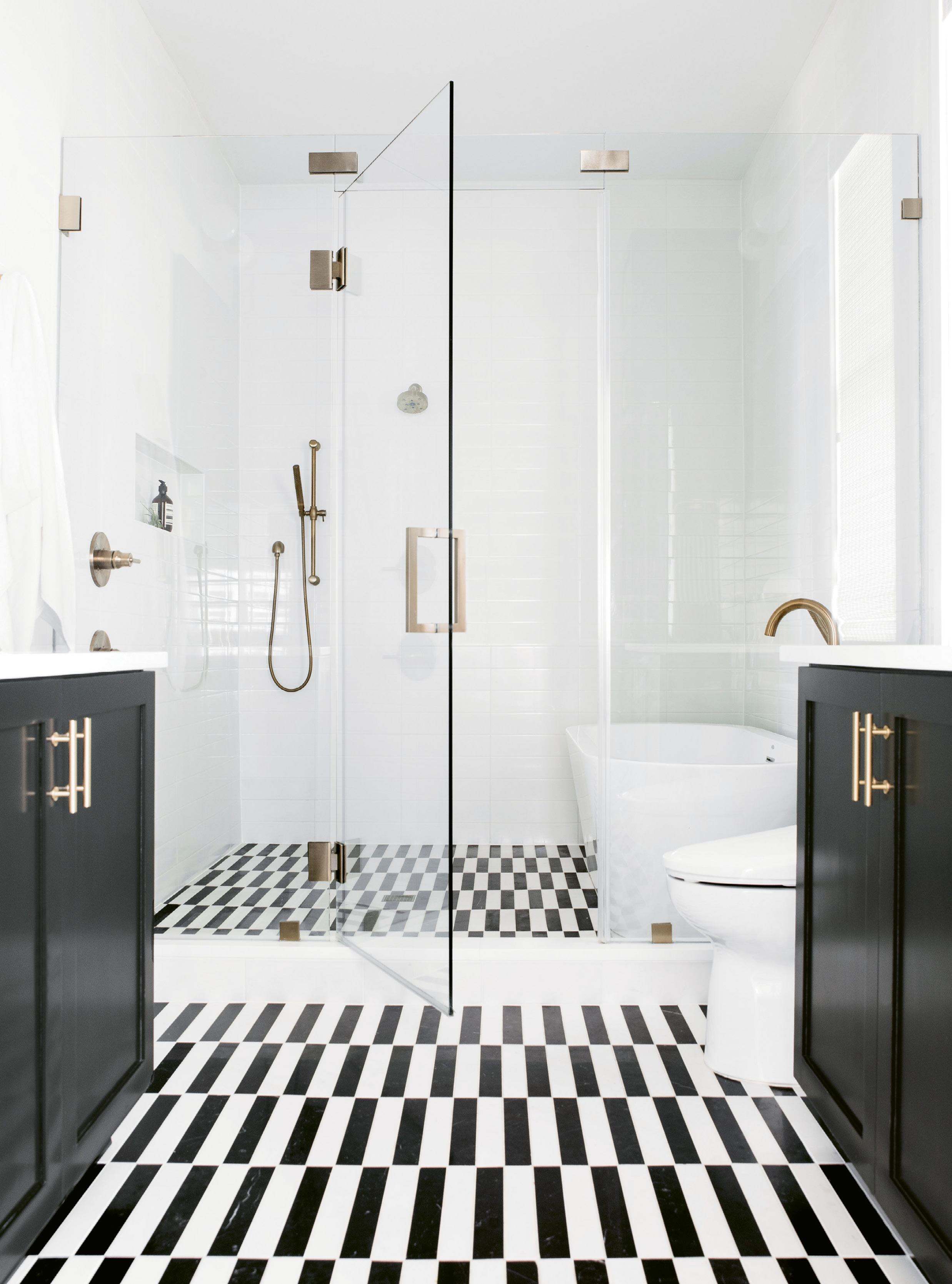 CLEAN &amp; SERENE: The master suite rivals boutique hotels for its comfort and style. A space-saving “wet room” configuration in the bath fits a walk-in shower and soaking tub, while glistening white-tile walls, cabinets covered in Benjamin Moore’s “Black Beauty,” and a custom-cut marble tile floor add drama.