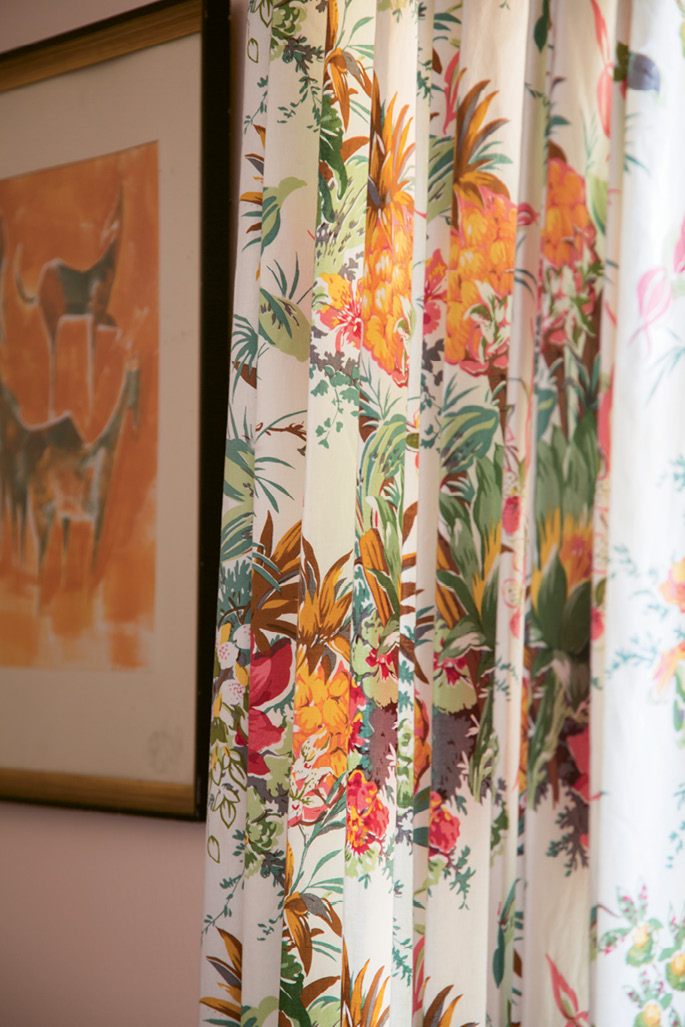 Floral drapes in punchy hues of orange, pink, and green add a beachy aesthetic to the home office.