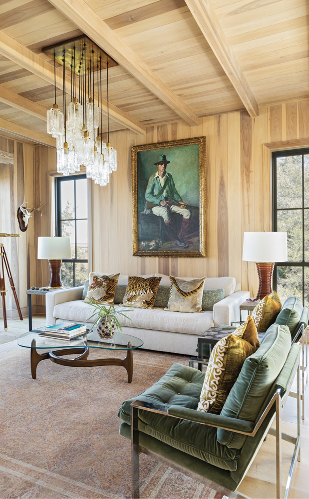 Conversation Space: The wood-paneled study is infused with warm tones. Chrome lounge chairs, upholstered in a Maharam cotton velvet, pick up on the green emanating from the dashing Hunter with Rabbits portrait by American painter Albert Edward Sterner (1936). A 1960s Kalmar light fixture with cascading, multi-tiered rectangular drops spills down to a mid-century Danish kidney coffee table, atop an antique rug.