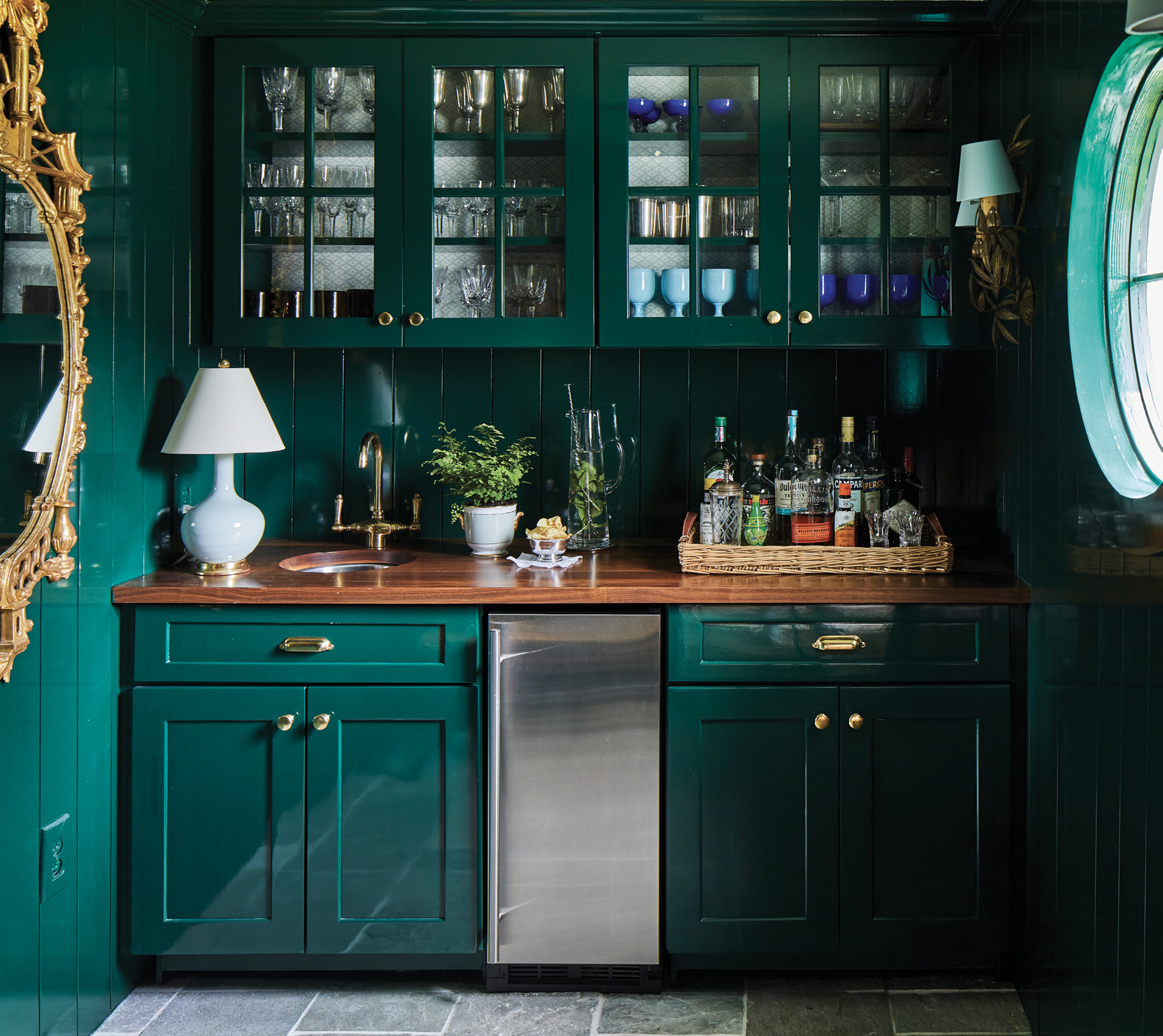 The dining space and lacquered bottle green bar room—where family silver and crystal shine through custom cabinetry—are all party.