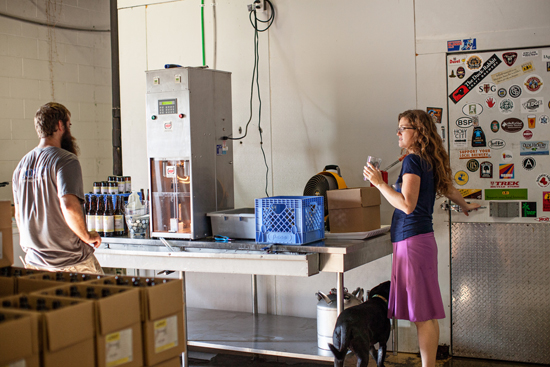 Jaime lets Teach, their dog, in the cooler (he was hot), while David is runs the bottling machine.