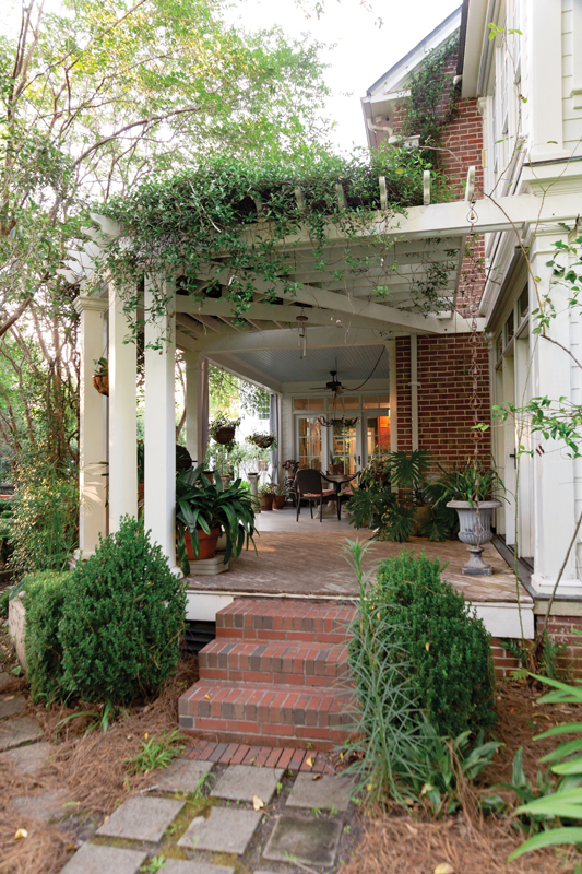 Porch Life: The Epsteins eventually expanded their kitchen onto part of the porch, adding walls of windows to maximize views of the garden. There’s still ample space for seating and potted plants beneath the pergola draped in star jasmine.