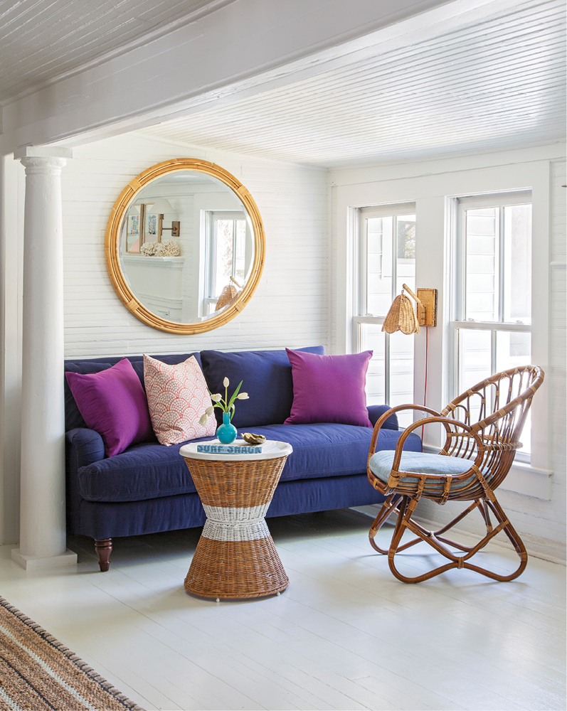 A Franco Albini rattan armchair from One of a Find Charleston offsets a blue love seat in a small seating area off the main living room.