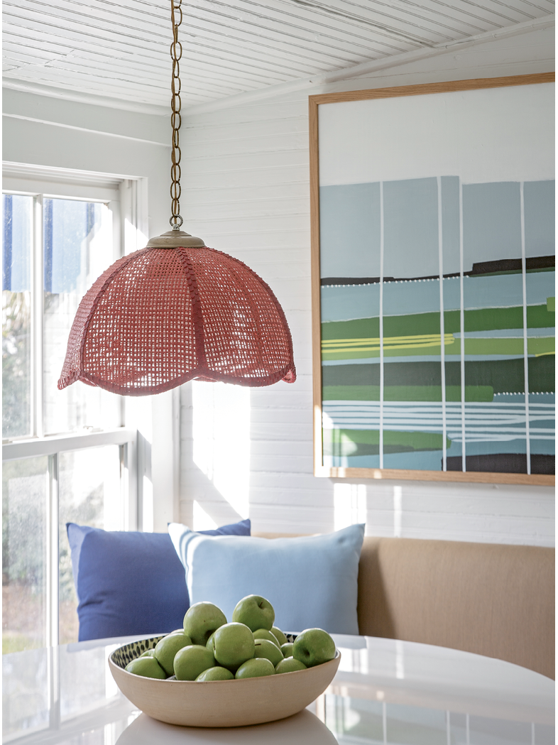 Color Play: A vintage red wicker pendant light in the breakfast nook is one of the homeowner’s favorite finds. A painting by Isle of Palms-based artist Cindy DeAntonio presides over the scene.