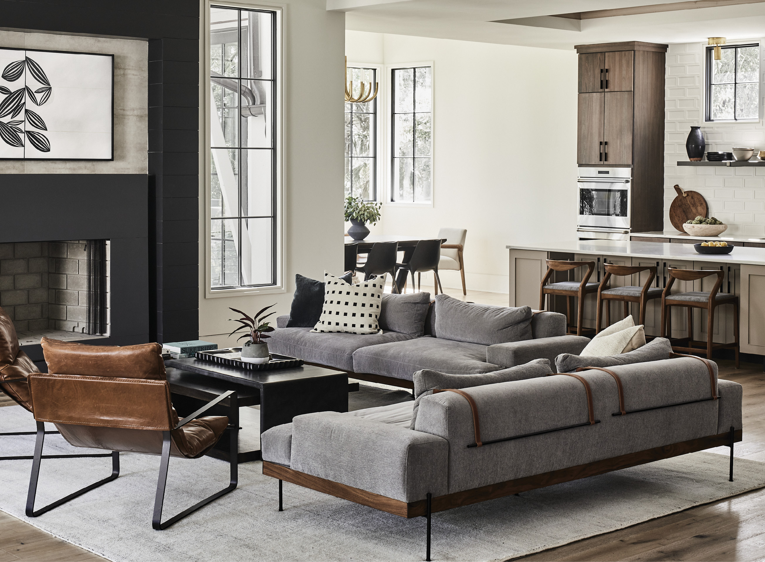 Anchored by a steel-wrapped fireplace surround with large-format tile above the mantel, the living space features low-profile iron and walnut sofas upholstered with a family-friendly performance fabric. A large wool rug helps define the space.