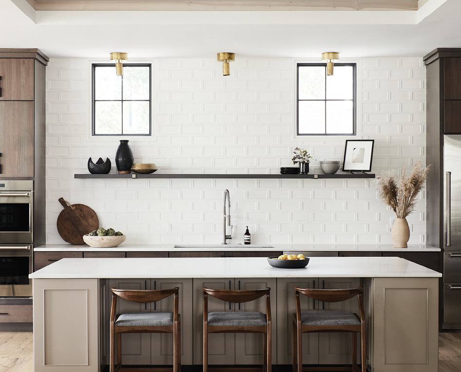 Clean Lined: The kitchen continues the industrial-modern vibe. Unlacquered brass light fixtures with an oversized canopy were designed by Jones to complement the Lyptus wood cabinets in a slate ebony finish while contrasting with the white tile