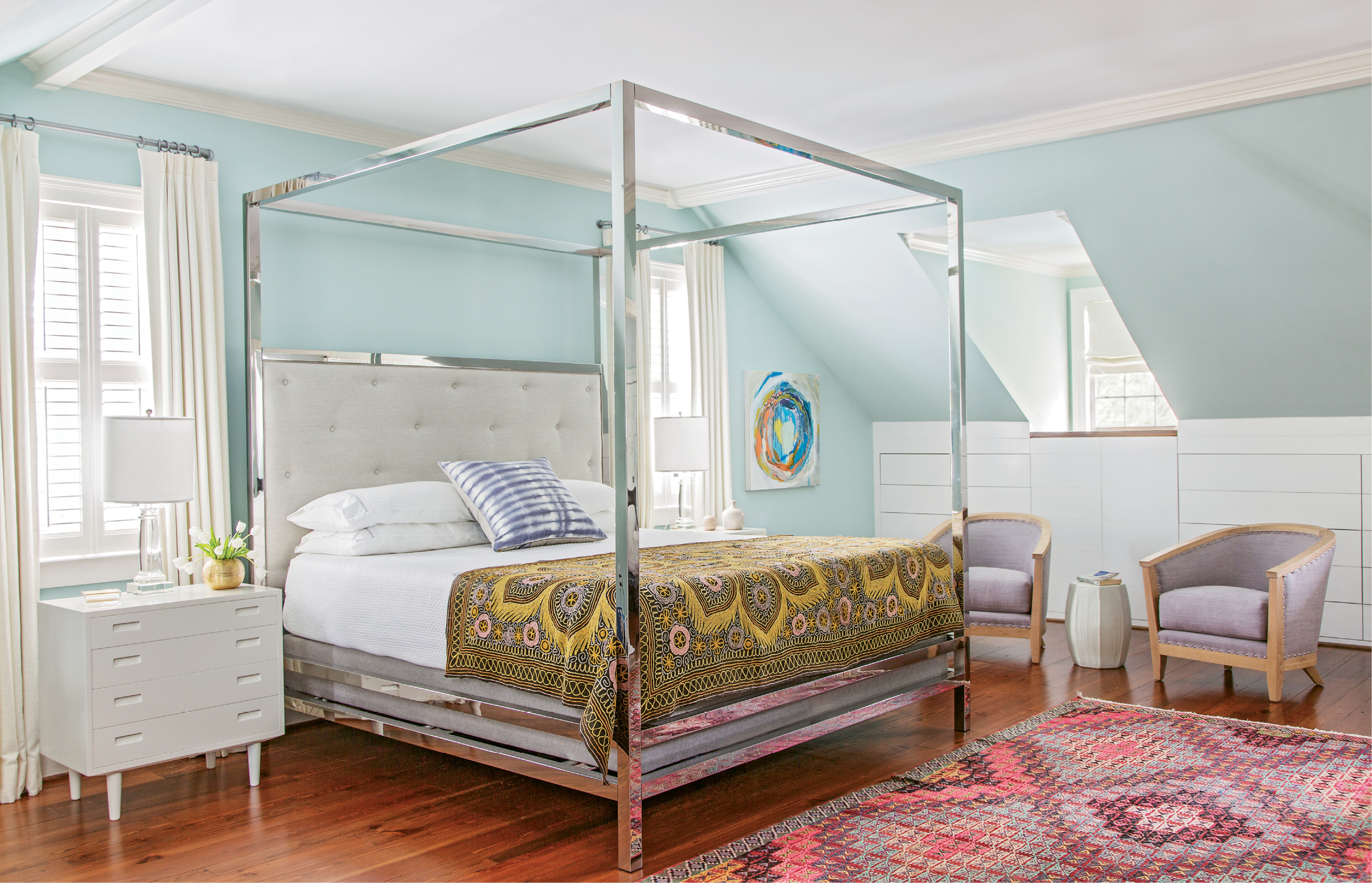 In the master bedroom, vintage textiles and mid-century nightstands add depth and texture to a streamlined canopy bed