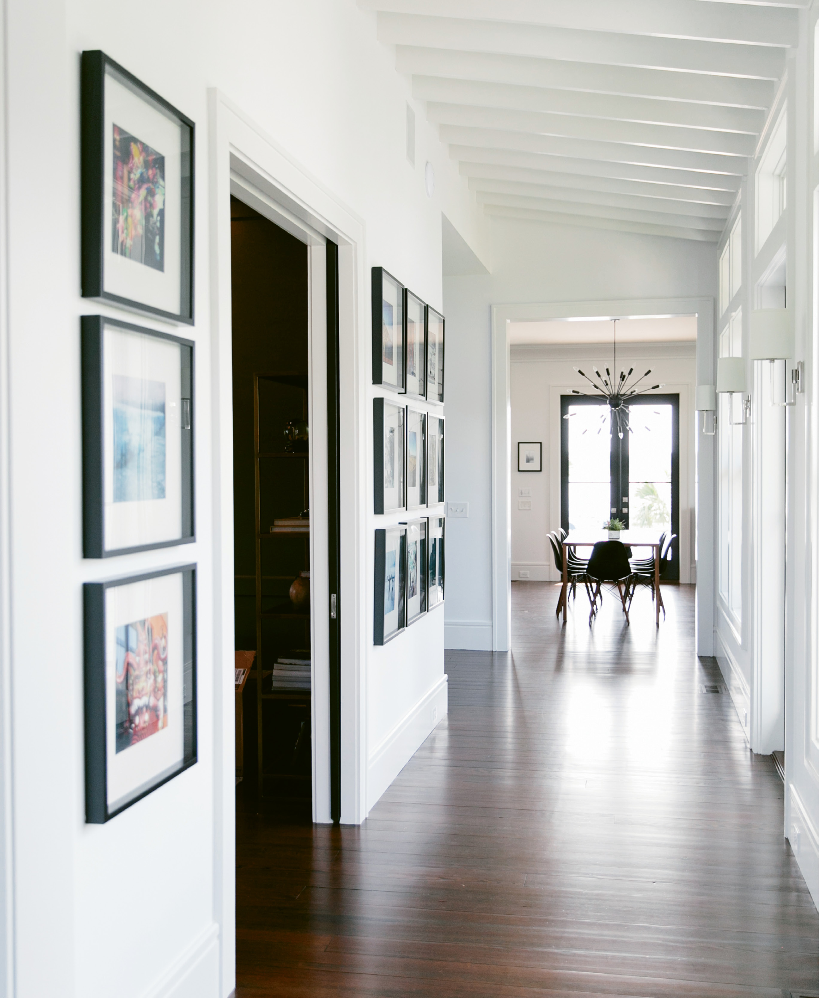 Melissa and Phil Clarke designed the entry hall’s slanted, beadboard ceiling to mimic the look of an enclosed porch. Her office is through the pocket doors to the left; at the end of the hall, the open cooking, dining, and living space feels like a totally separate zone.