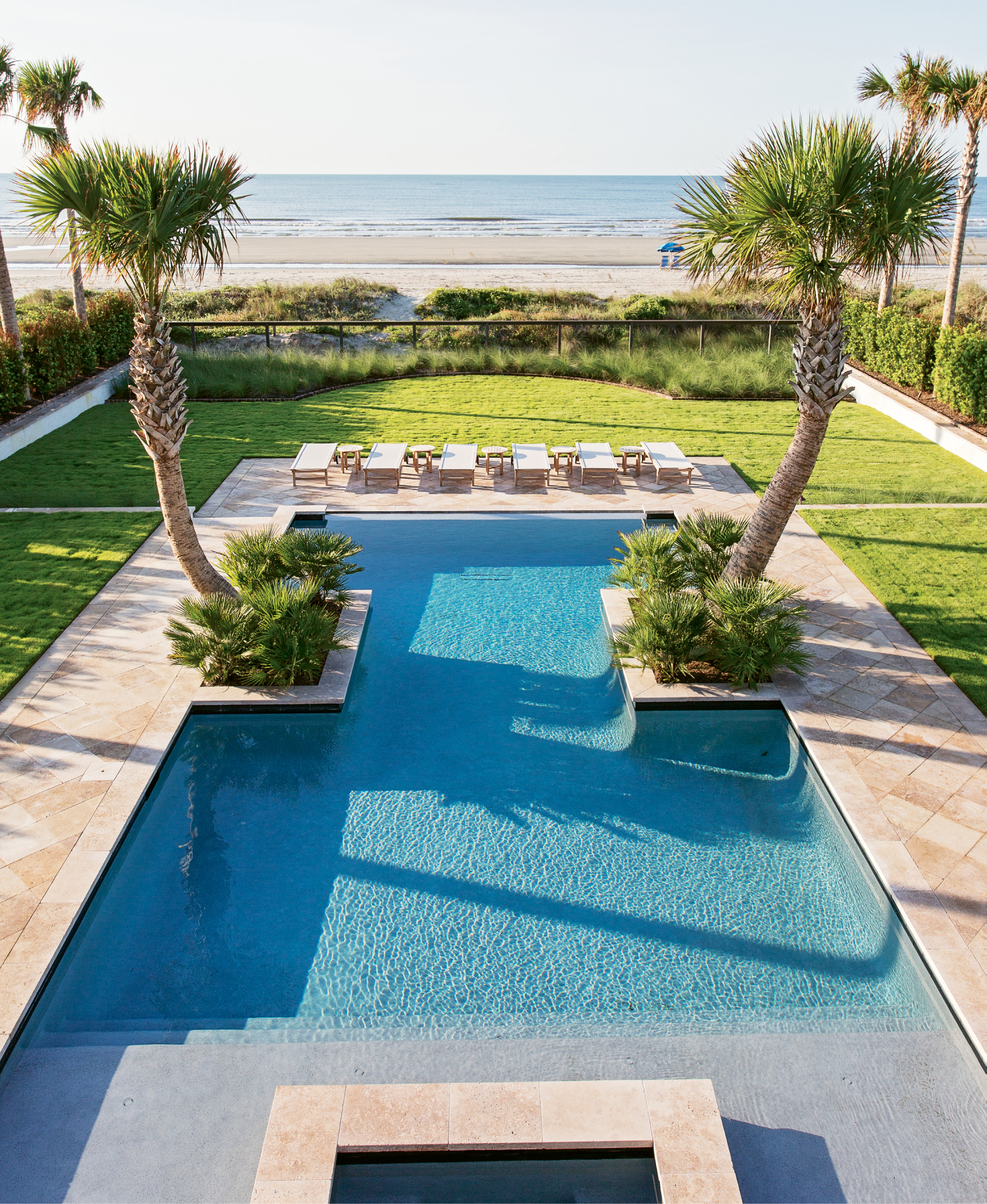An I-shaped pool, mirror-image palmetto trees, and luxe Kingsley Bate patio loungers mean the Lamachs’ own yard provides a view that rivals the nearby ocean.