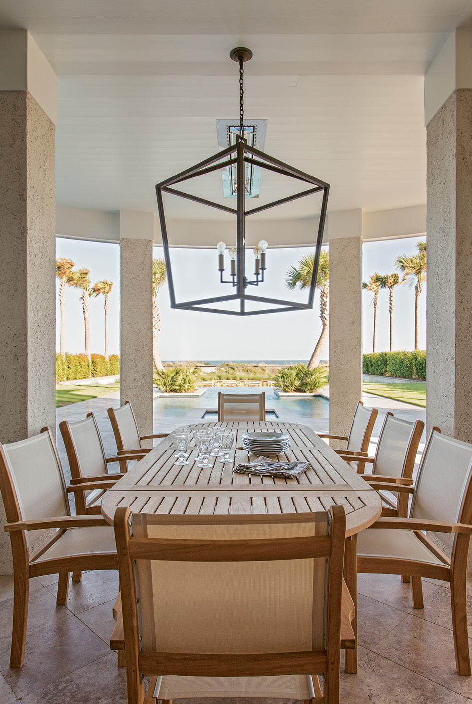 The View from Here: A teak dining table and Currey and Company light fixture set the stage for elegant outdoor dining.