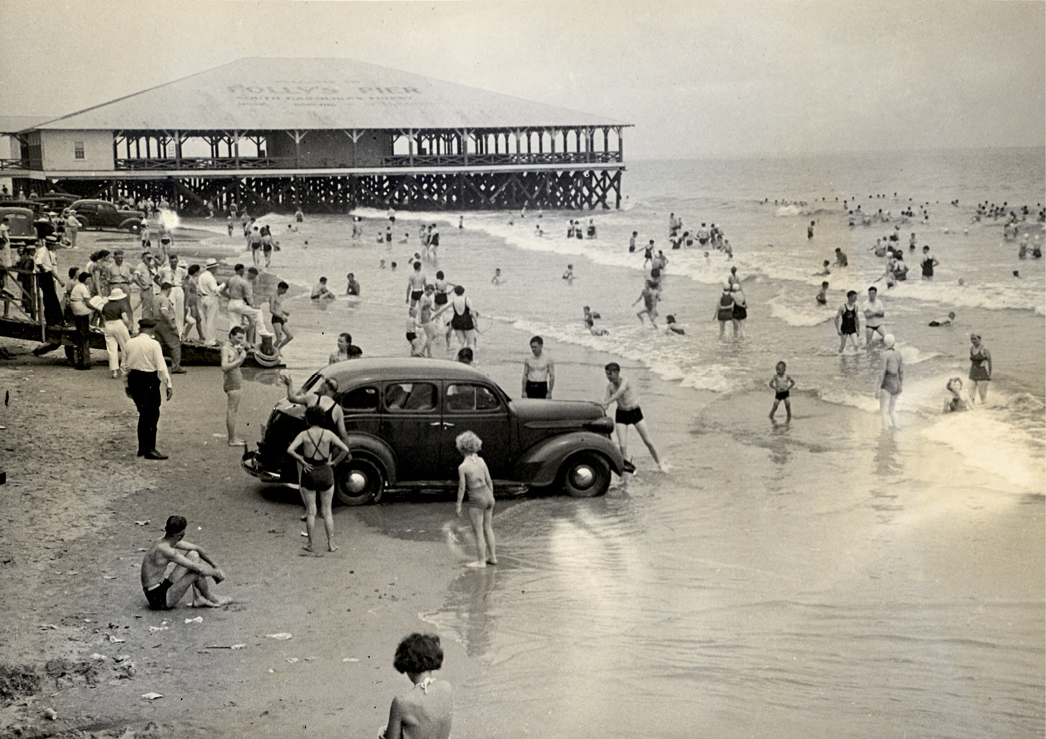 A car parked on the beach gets caught in the incoming tide, circa 1950.