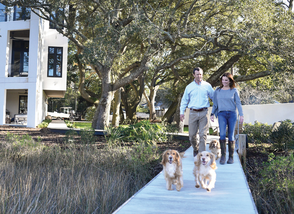 Owners Alix and Mark Bragg pictured with their three pups, Kay, Peanut, and Junior) tackled this conundrum by taking a cue from the trees and building upward. The finished project marries a bold modern design with a soft Mediterranean warmth in a special Lowcountry setting.