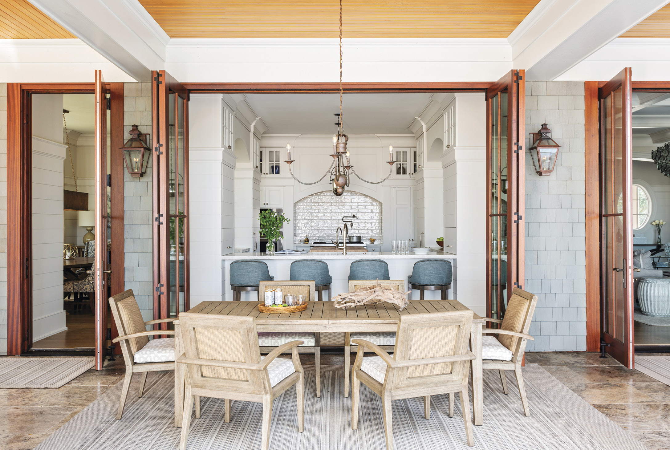 EATING IN &amp; OUT: A floating kitchen anchors the home, tying the indoor and outdoor living spaces together. The alfresco Lloyd Flanders dining table and chairs, purchased at GDC Home, is as accessible to the chef as the formal dining room.