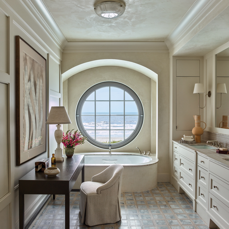 A BainUltra tub, Made Goods “Conrad” desk, and upholstered vanity chair create a luxurious setting in the bathroom.