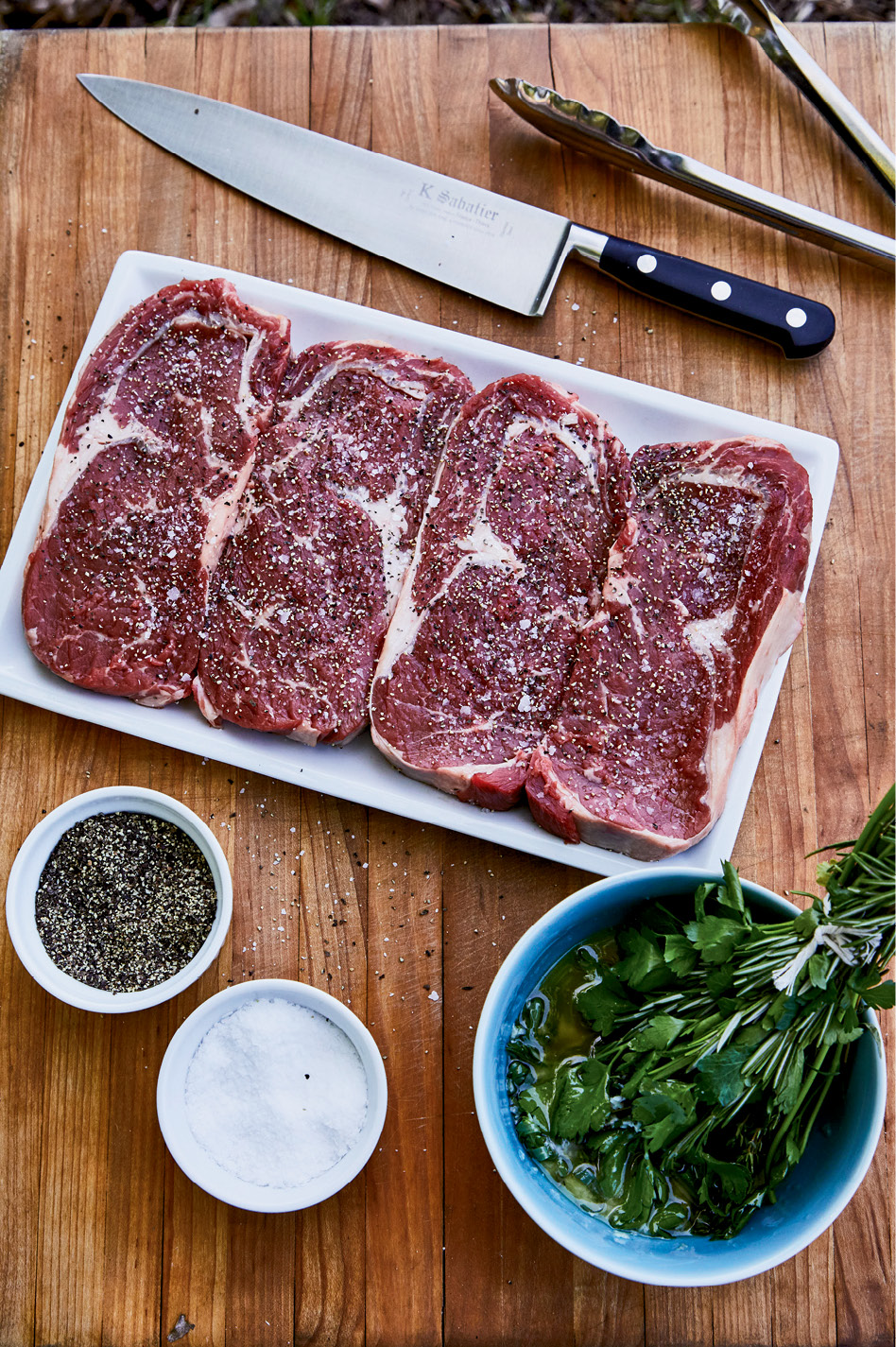 Raise the Steaks: The pitmaster seasons rib eyes simply with salt and pepper and then glazes the meat using a savory herb bundle of thyme, rosemary, parsley, and tarragon dunked in melted garlic butter.
