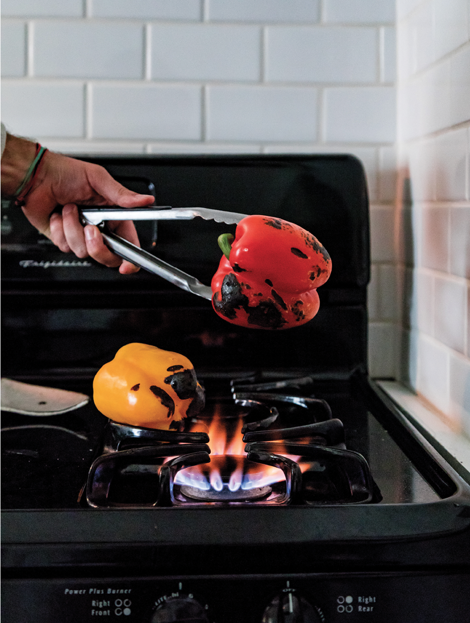 Reitz roasts peppers over an open flame, turning constantly, until they’re charred on all sides.