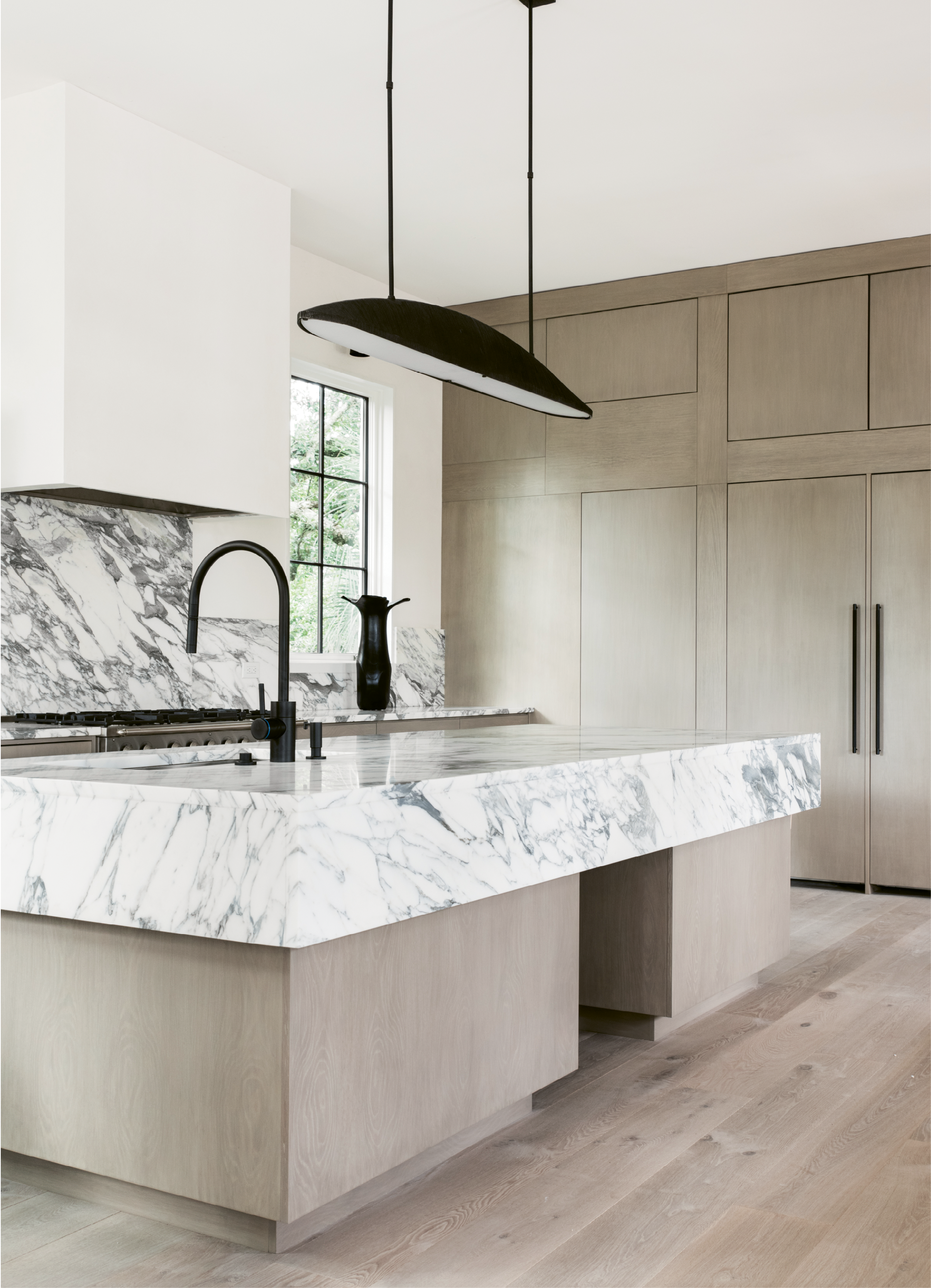 In the light and airy kitchen, white marble countertops with bold black veining make a strong visual impact.