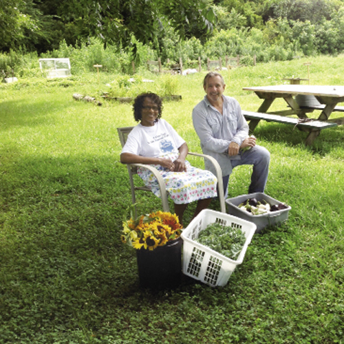 A volunteer collects goods from Sweetgrass Garden farm manager Dale Snyder (right)