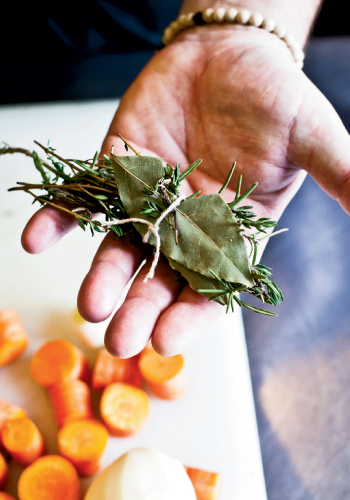 To create a bouquet garni for his vegetable soup, Perig ties together rosemary and thyme sprigs and a bay leaf.