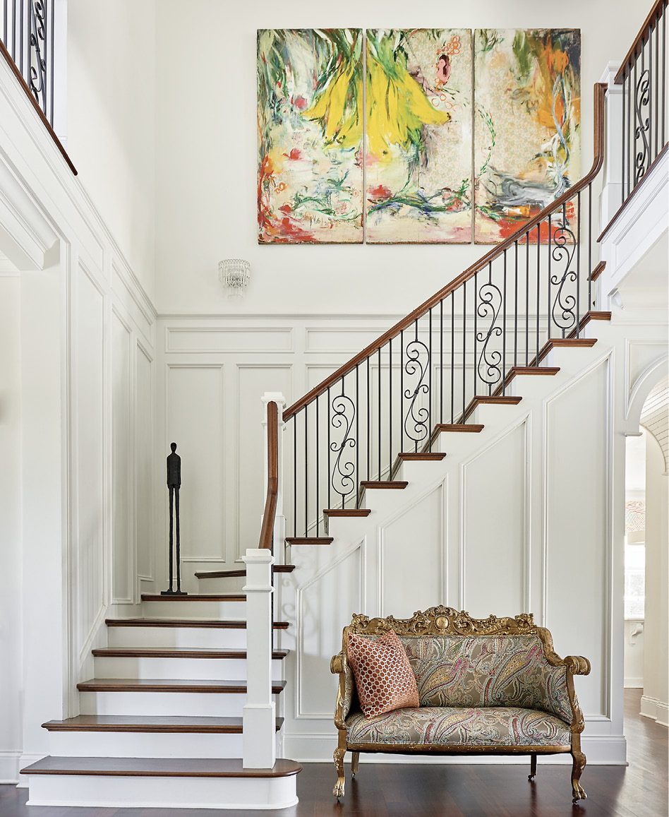 In the main stair hall, an abstract triptych by Jeannie Weissglass complements the classic English plaid from Osborne &amp; Little on the antique French settee. The painting, says Mitchell, inspired the design throughout the home.