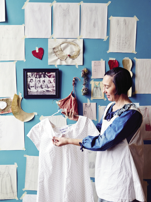 At the 701 Center for Contemporary Art, the new Madame Magar collection of muslin and canvas frocks hangs on pulleys and  hooks. As part of the exhibit, Charleston-based designer Leigh Magar has created a temporary studio workshop within the gallery space so  visitors can see her sewing, dyeing, and adding penciled lettering to the dresses.