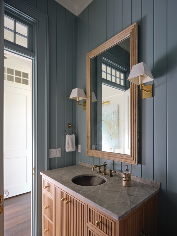 In the downstairs powder room, a pair of Vaughan sconces from England flank a French reeded-bamboo mirror from Foxglove Antiques in Atlanta above a custom vanity by Dutchman Furniture.