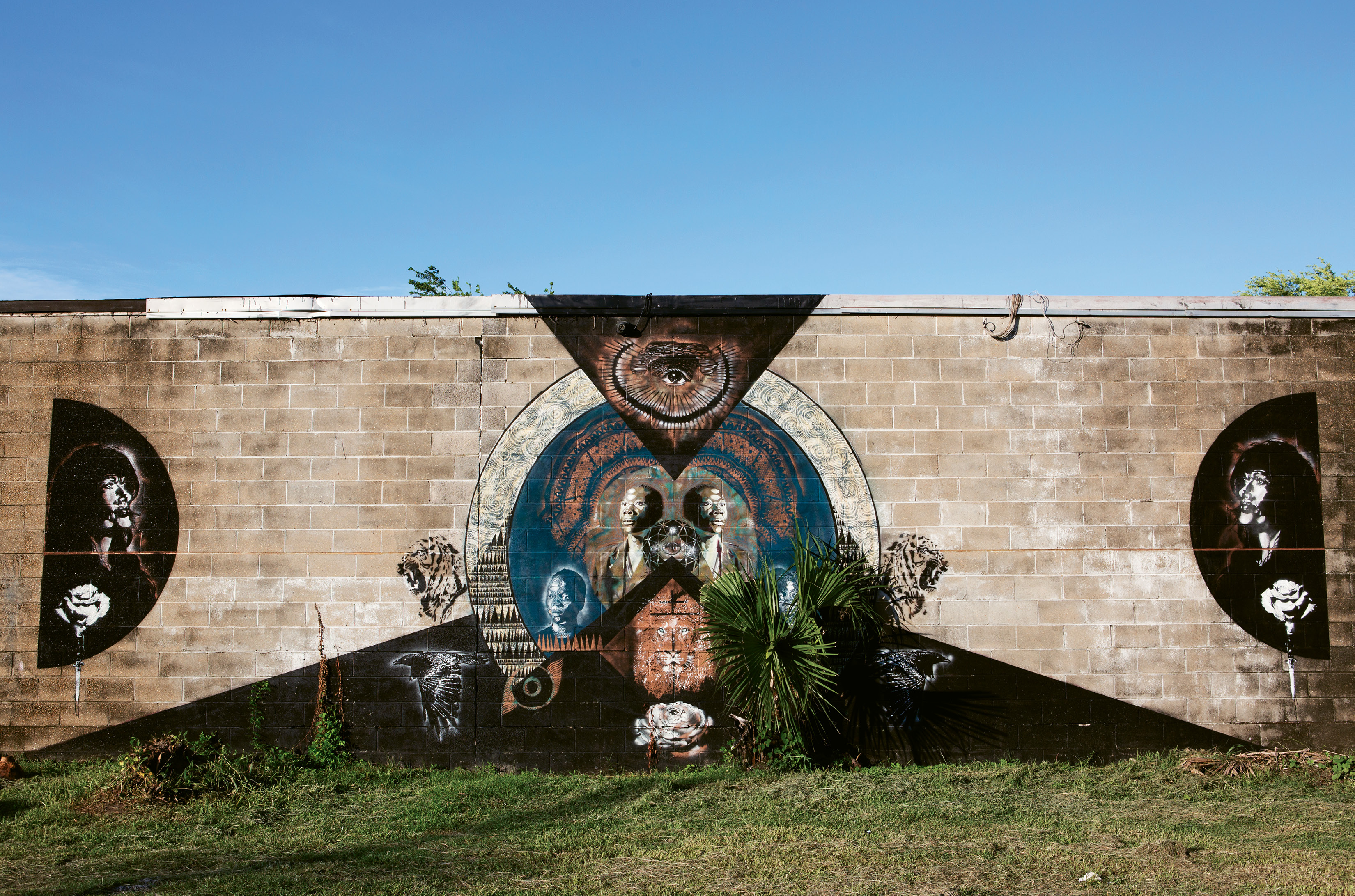 Living Stone by RC Hagans,  June 2015  (Huger &amp; Hanover streets). Created alongside seven other works for Enough Pie’s “AWAKENING III: SOLSTICE” community art event, this mural by Alabama-based artist RC Hagans was inspired by a home for boys orphaned by violence and disease in Zambia. he says The central figure is the elder brother and protector: “His lion’s heart and quiet strength make him the perfect watcher for all who walk these streets. If you are weak, may you become strong, if you are strong, protect the weak.”