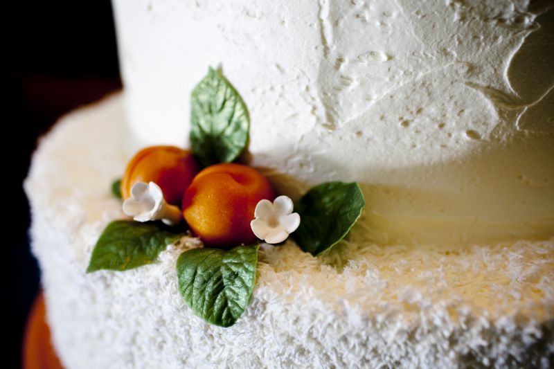 COLOR-CODED CONFECTION: In keeping with the wedding’s “apricot and azure” theme, the traditional white butter cake, made by Wedding Cakes by Jim Smeal, was garnished with marzipan apricots. The wooden cake stand was painted to match the pantone shade of the theme, as well.