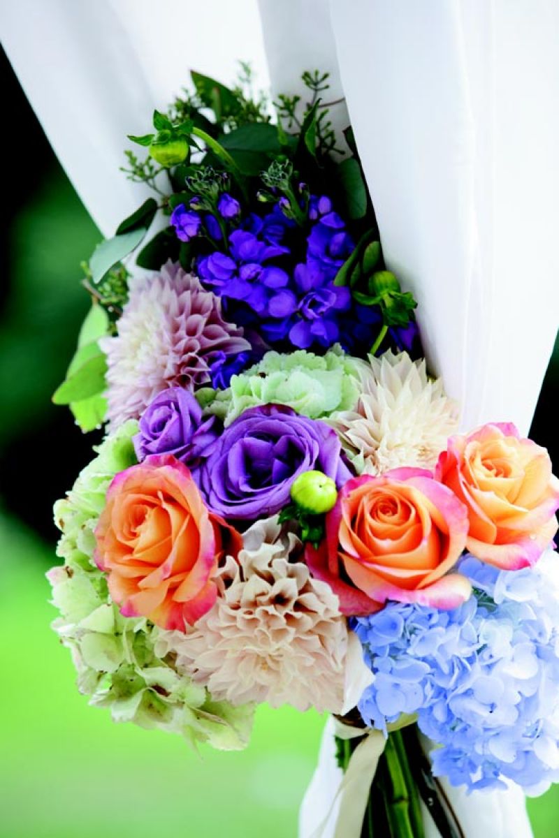 ALL TIED UP: To soften the crisp white curtains of the reception tent, stems created bright floral tie-backs.