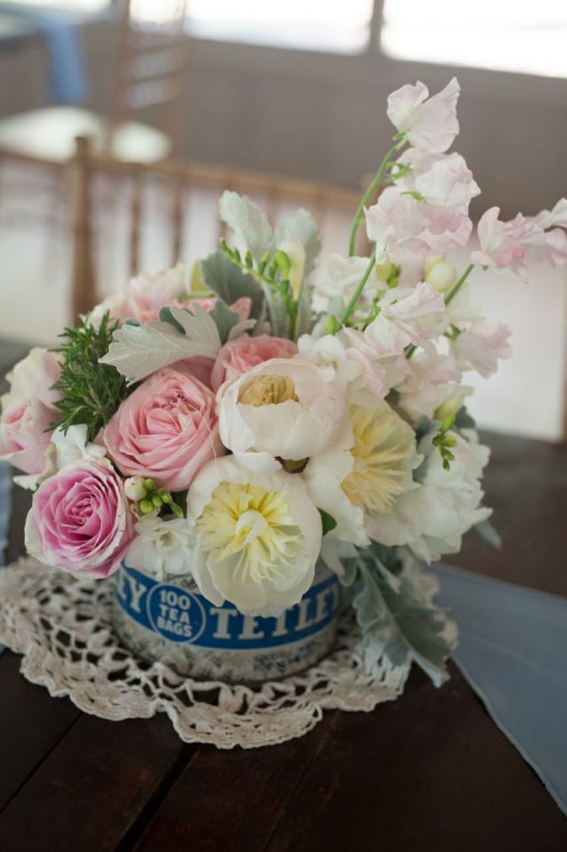 PRECIOUS METAL: For vintage-inspired centerpieces, blush bouquets of roses, peonies, carnations, and rosemary were tucked into old-fashioned tea-tins and set atop lace doilies.